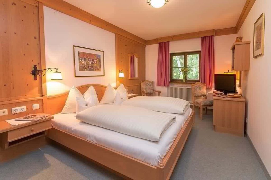 Behagliches Zimmer im Erlhof mit Doppelbett, Sitzbereich und Blick ins Grüne.