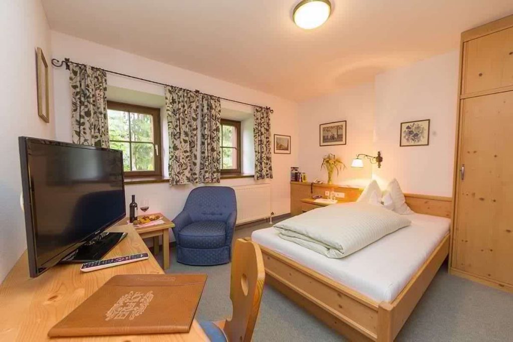 Gemütliches Zimmer im Erlhof mit Balkon, TV, Schreibtisch und Panoramablick auf Natur.