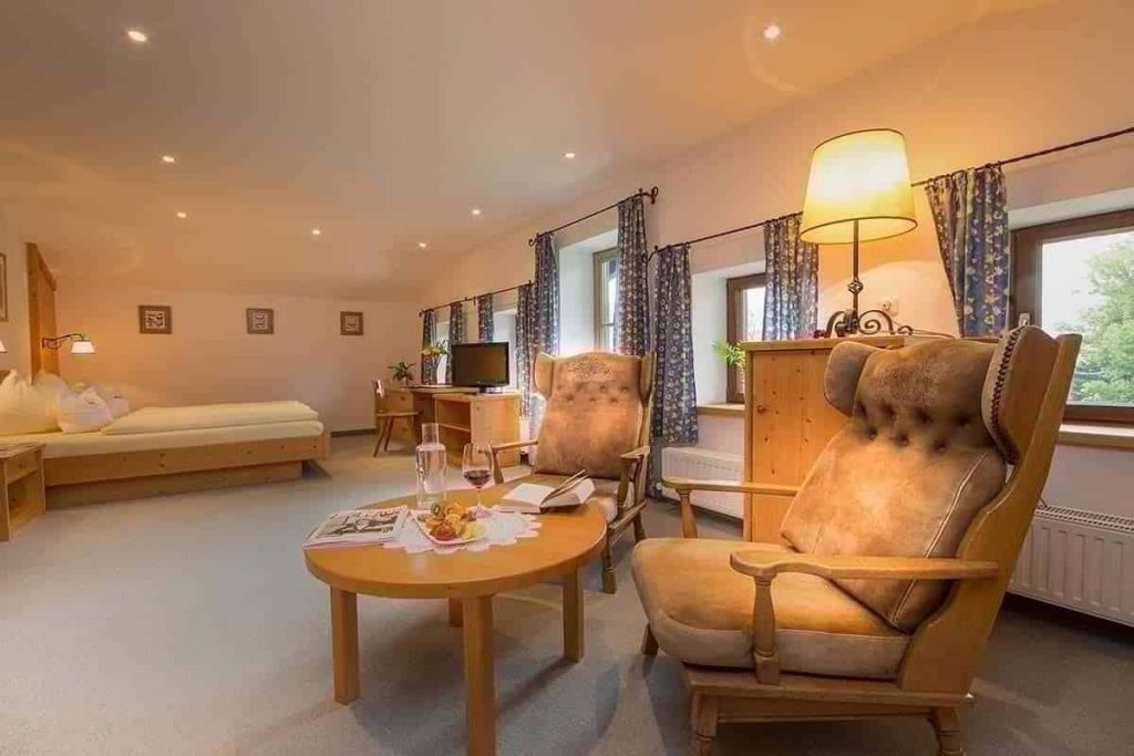 Gemütliches Zimmer im Erlhof mit komfortablen Sesseln, Tisch und Blick auf die Natur.