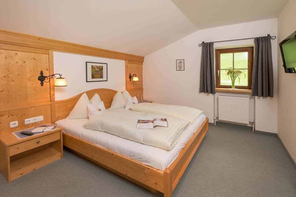 Komfortables Doppelzimmer mit Holzmöbeln, gemütlicher Atmosphäre und Blick auf die umliegende Natur.