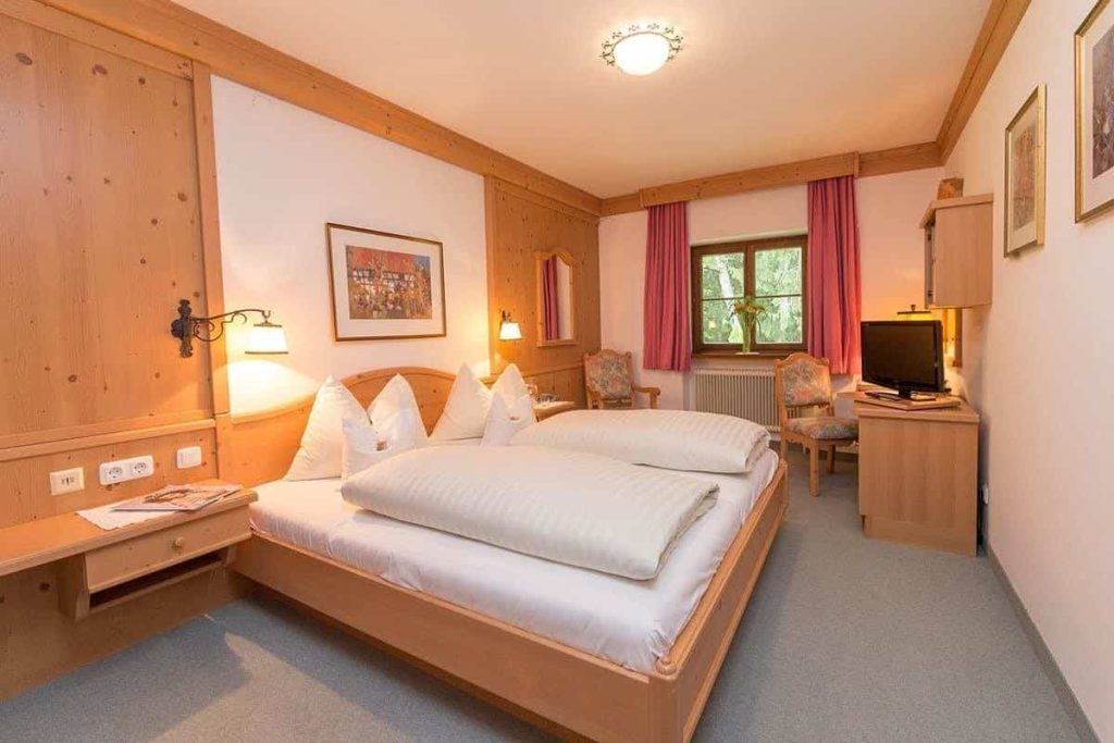 Gemütliches Doppelzimmer im Hotel Erlhof mit Holzverkleidung und Blick durch das Fenster.