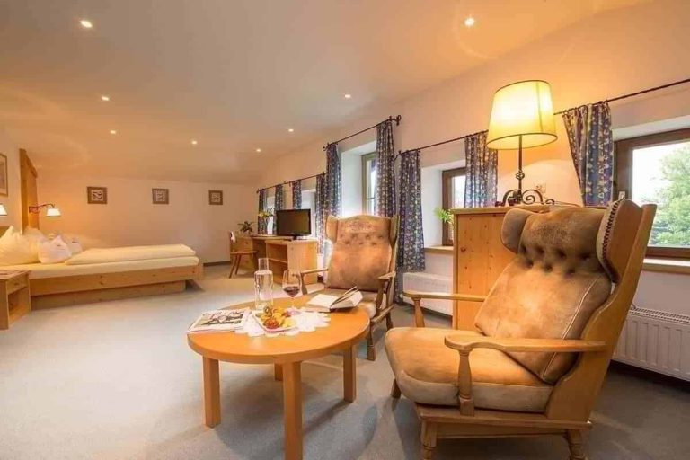 Gemütliches Zimmer im Hotel Erlhof mit zwei Sesseln, Tisch und Blick auf den Zeller See.