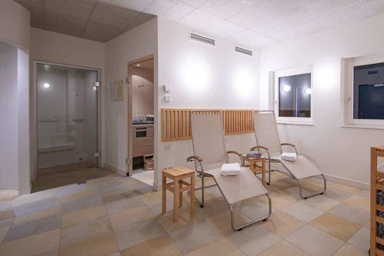 Wellnessbereich im Erlhof mit Liegen und Sauna, modernes Ambiente zur Entspannung.