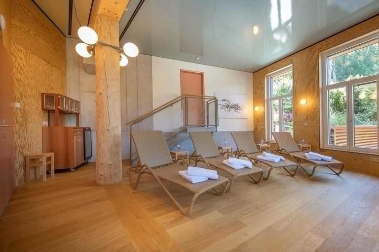 Entspannungsbereich mit Liegen, Holzdetail und großen Fenstern im Landhotel Erlhof.