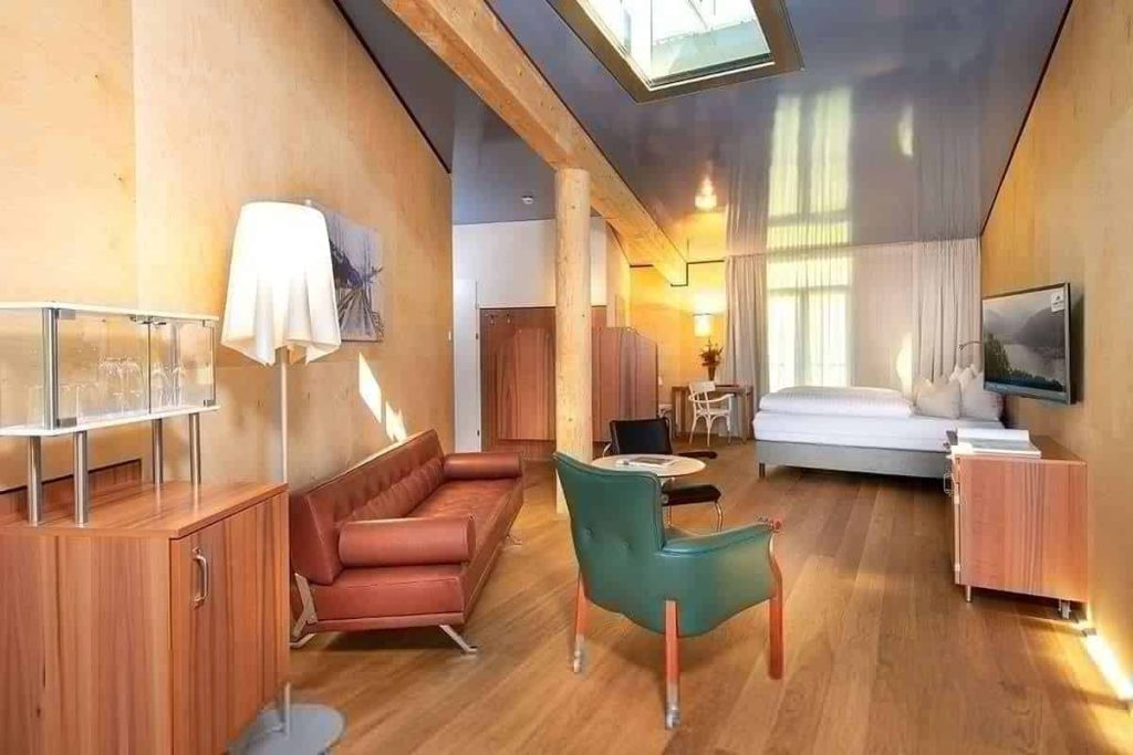 Moderner Hotelraum mit Sitzbereich, großen Fenstern und stilvoller Einrichtung.